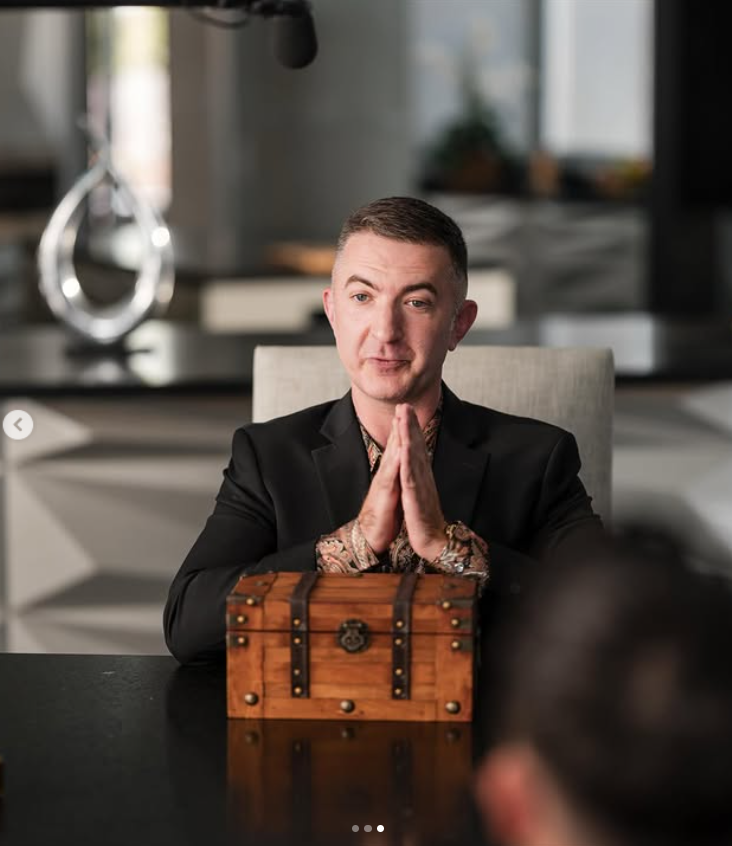 Adam Chisnall on set, seated behind a mysterious wooden chest during a scene, as posted on October 26, 2025 | Source: Instagram/theadamchisnall