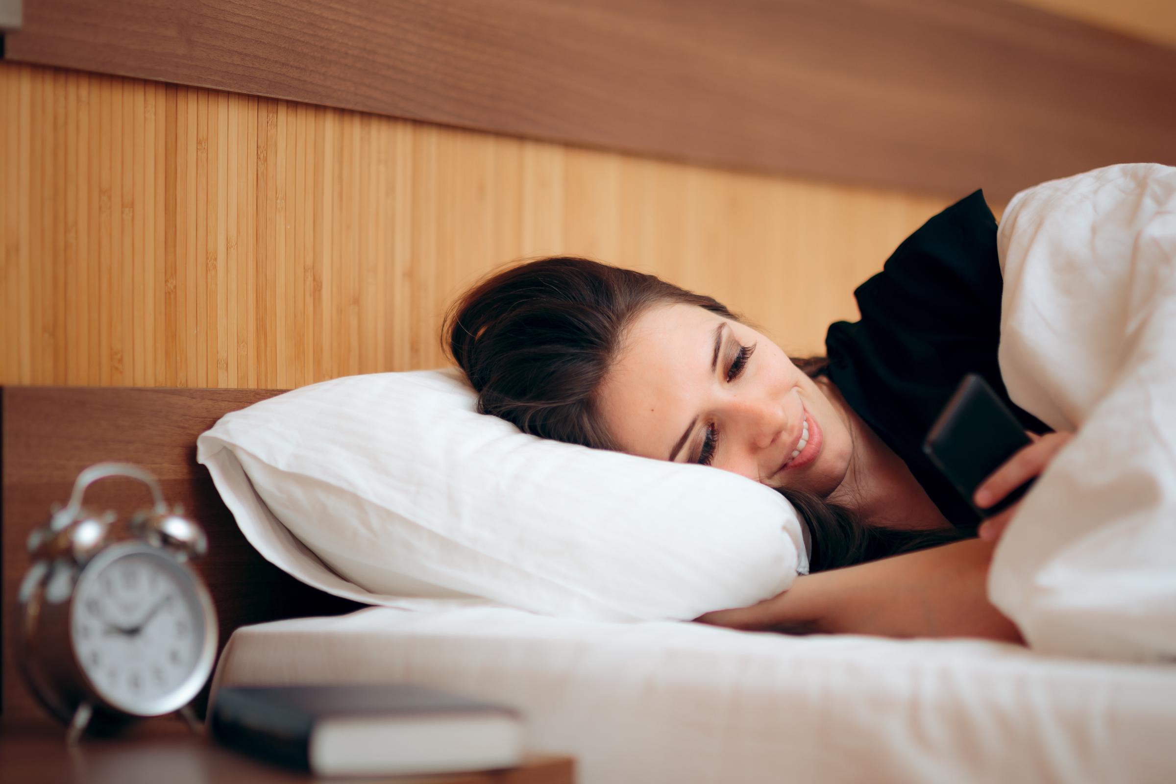 A woman watching on her phone while lying in bed | Source: Shutterstock